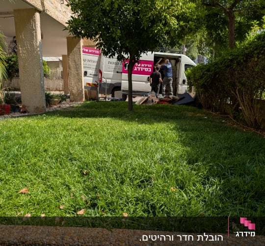 שני אנשים מעמיסים ציוד לרכב מסחרי לבן